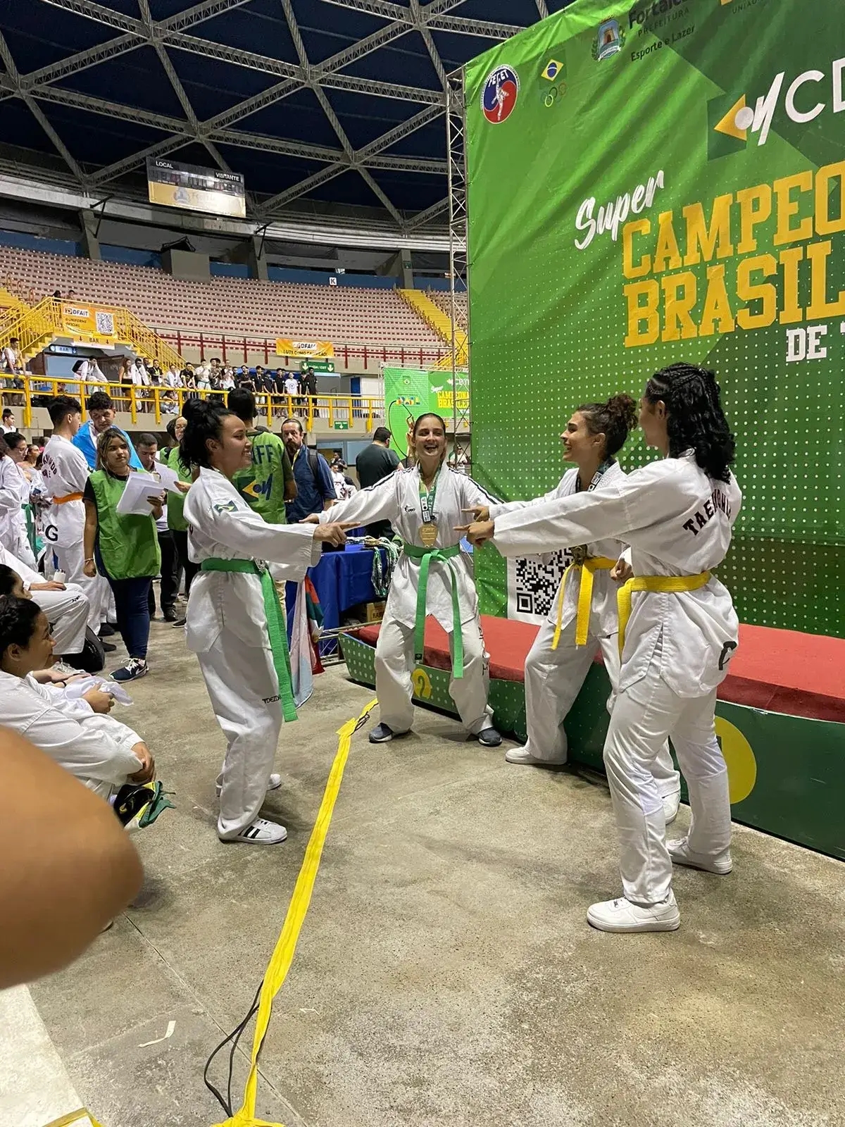 Quatro alunas praticantes de taekwondo fazendo uma brincadeira descontraída…